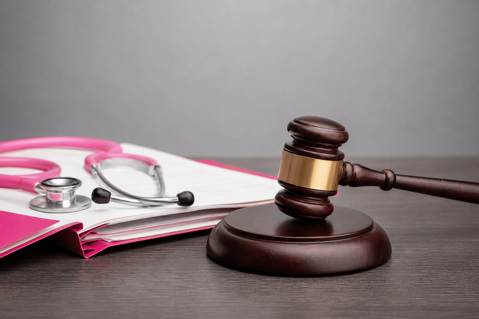 Ein Richterhammer liegt neben einer aufgeschlagenen Patientenakte und symbolisiert Haftungsfolgen bei Dokumentationsmängeln.
